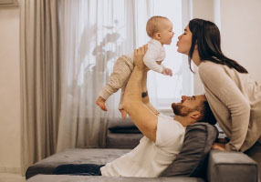 pai levantando bebê e mãe o beijando