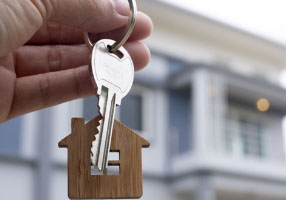 pessoa segurando uma chave com uma bonita casa ao fundo